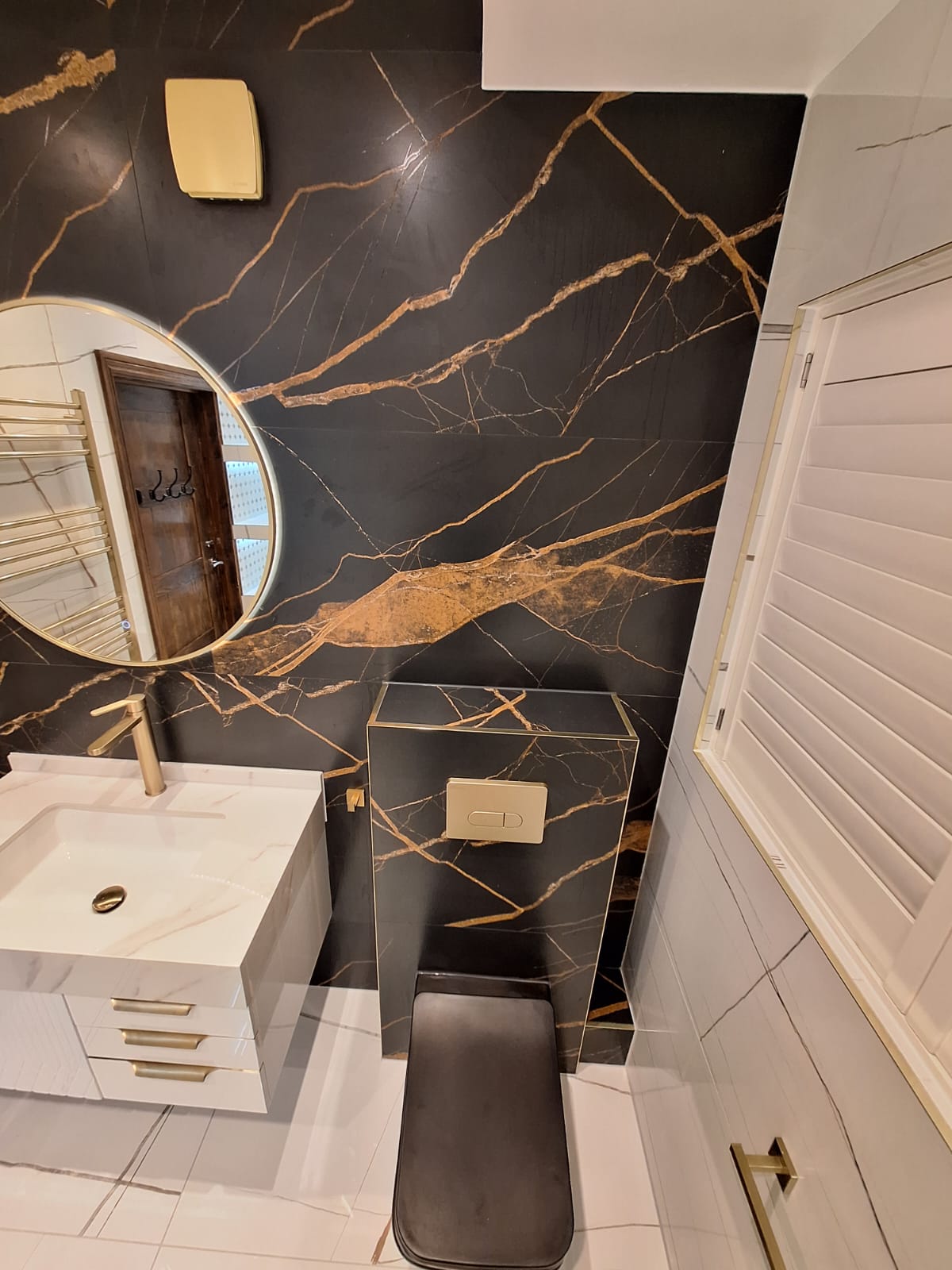 White vanity with ribbed front, brushed brass handles and statuario top